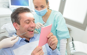 A dentist showing a patient a model of a dental implant during osseointegration