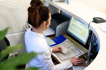 a front desk worker on a computer checking paperwork
