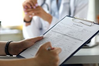 a person filling out patient paperwork on a clipboard