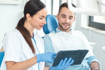 a dentist speaking with a patient sitting in a chair
