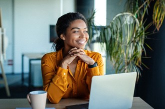 a smiling woman in an orange shirt with a cup of coffee