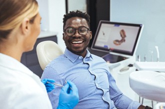 a smiling man speaking with his dentist