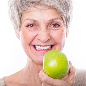 Smiling senior woman holding an apple