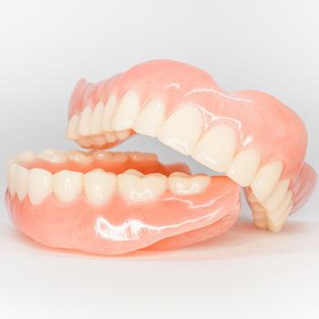 Full set of shiny dentures on white surface