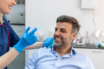 Patient smiling at dental assistant holding clear aligner