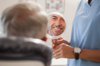 Man smiling at reflection in handheld mirror