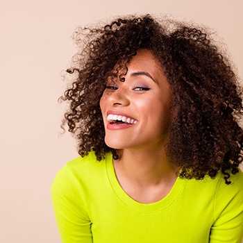 Woman in chartreuse sweater with curly hair smiling