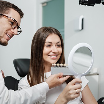 Dentist holding shade guide up to woman’s teeth