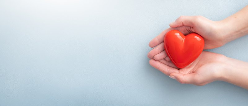 woman’s hands holding red heart with care