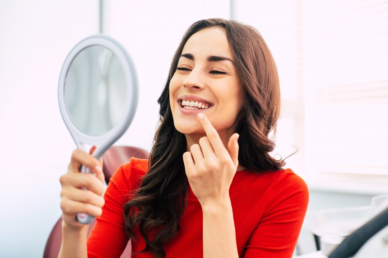 Woman smiling at reflection in dentist's office