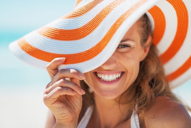 A woman smiling during the summertime after receiving cosmetic treatment.